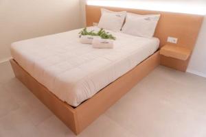 uma cama grande com lençóis brancos e plantas em Carvalheira Country House - Gerês em Braga