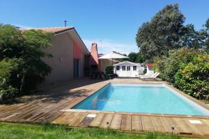- une piscine avec une terrasse en bois à côté d'une maison dans l'établissement Grande maison familiale piscine et jardin, à Gujan-Mestras