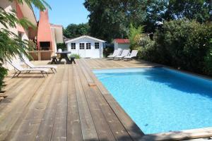 einen Pool mit Stühlen und eine Holzterrasse in der Unterkunft Grande maison familiale piscine et jardin in Gujan-Mestras