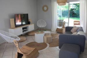 - un salon avec un canapé, des chaises et une télévision dans l'établissement Grande maison familiale piscine et jardin, à Gujan-Mestras
