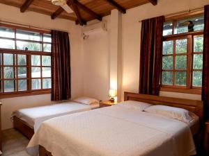 2 Betten in einem Schlafzimmer mit 2 Fenstern in der Unterkunft Banana Lodge in Puerto Misahuallí