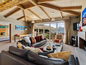 a living room with leather furniture and a large window at Chambers City Centre Penthouse in Queenstown