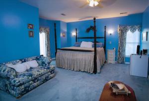 Dormitorio azul con cama y sofá en Rabbit Creek Bed & Breakfast en Versailles