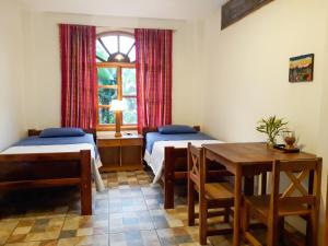 プエルト・ミサウアリにあるBanana Lodgeのベッド2台、テーブル、窓が備わる客室です。