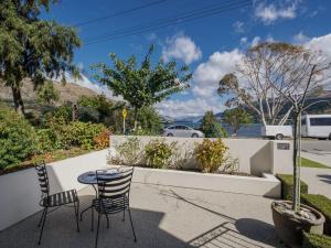 a patio with a table and chairs and a fence at Lake Avenue Studio in Queenstown