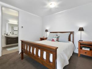 - une chambre avec un lit en bois et un miroir dans l'établissement Lake Avenue Studio, à Queenstown