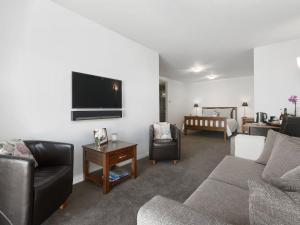 a living room with a couch and a tv on a wall at Lake Avenue Studio in Queenstown