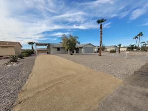 a dirt road in front of a house with a palm tree at NEW! Family Lake Havasu Home Close To Off-Roading And London Bridge! in Lake Havasu City