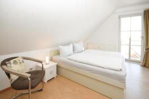 ein Schlafzimmer mit einem Bett, einem Stuhl und einem Fenster in der Unterkunft Sperlingslust in Scharbeutz