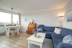 uma sala de estar com um sofá azul e uma mesa em Haus Beau Rivage Wohnung 41 em Scharbeutz