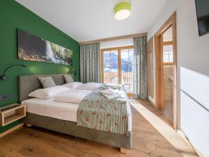 een slaapkamer met een groot bed met een groene muur bij Luxury chalet with 5 bathrooms, near a small slope in Neukirchen am Großvenediger