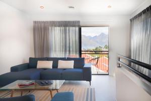 a living room with a blue couch and a balcony at Close to the Action - In Town - Spa Pool in Queenstown