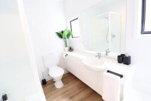 a white bathroom with a toilet and a sink at Close to the Action - In Town - Spa Pool in Queenstown +21 photos