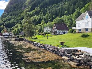 a house and a stone wall next to a body of water at 6 person holiday home in øystese in Øystese
