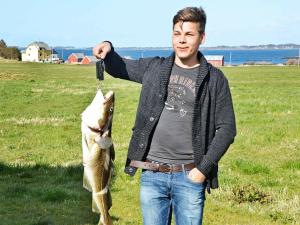 a man holding a fish in a field at 11 person holiday home in Fj rtoft in Fjørtoft