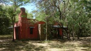 un antiguo edificio rojo en medio de árboles en La Farfalla en La Población