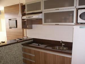 a kitchen with a sink and a white refrigerator at Duplex Apto Setor Hoteleiro Norte com serviço diário de limpeza in Brasilia