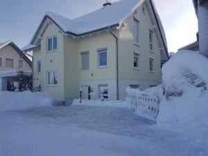 a house covered in snow with a fence at Ferienwohnung Dressler in Wolfegg
