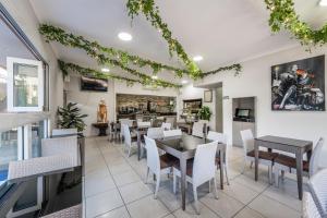 a dining room with tables and white chairs at Athena Motel Apartments in Toowoomba