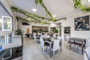 uma sala de jantar com mesas e cadeiras brancas em Athena Motel Apartments em Toowoomba