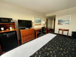 Habitación de hotel con cama, escritorio y TV. en Best Western Plus Waterville Grand Hotel, en Waterville