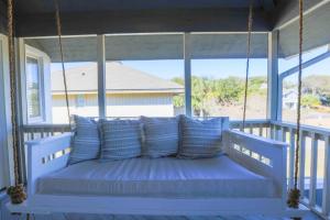 a porch swing with blue pillows on a porch at Beachside Cottage in Isle of Palms +42 photos