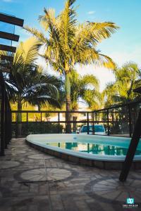 a swimming pool with palm trees in the background at Residencial Solar Del Nieto in Garopaba