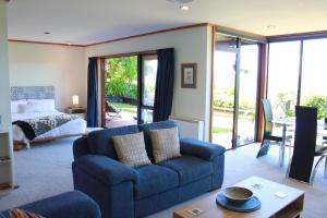 a living room with a blue couch and a bed at Lake View Garden Apartment in Taupo