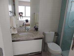 uma casa de banho com um WC, um lavatório e um espelho. em Apartamento mobiliado novo Metrô Luz em São Paulo