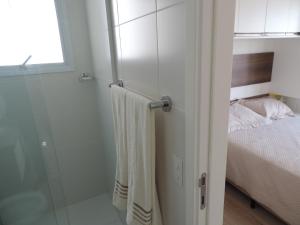 a bathroom with a glass shower and a bed at Apartamento mobiliado novo Metrô Luz in São Paulo