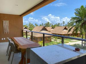 a balcony with a table and a view of a house at Flat 113 Eco Resort Praia dos Carneiros in Praia dos Carneiros