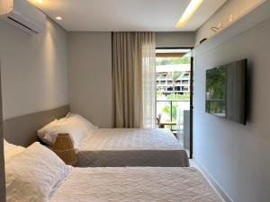 ein Hotelzimmer mit zwei Betten und einem Fernseher in der Unterkunft Flat 113 Eco Resort Praia dos Carneiros in Praia dos Carneiros + 38 Fotos