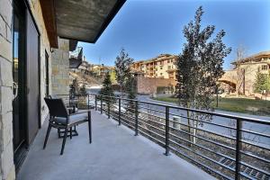 a balcony with a chair and a view of a river at Modern Ski In Out 2 BR in Canyons Village in Park City