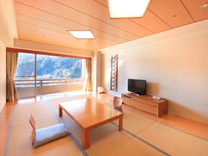 Akazawa Onsen Hotel في إيتو: غرفة معيشة مع طاولة وتلفزيون