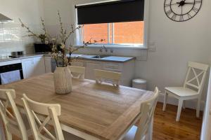 a kitchen with a wooden table with chairs and a vase at Hazeldene - The Best Location In Town! in Myrtleford