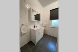 a white bathroom with a sink and a mirror at Hazeldene - The Best Location In Town! in Myrtleford +20 photos