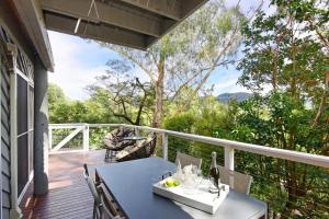 a table and chairs on a deck with a view at Treetops - Three bedroom home with great views, in the village! in Kangaroo Valley