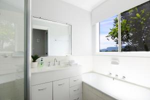 a white bathroom with a sink and a mirror at Treetops - Three bedroom home with great views, in the village! in Kangaroo Valley