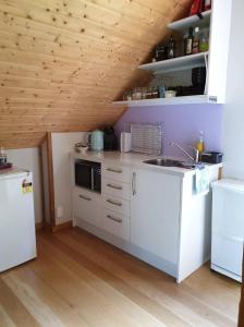 cocina con armarios blancos y techo de madera en Rail Trail Retreat Loft en Alexandra