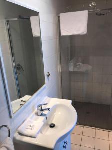W białej łazience znajduje się umywalka i lustro. w obiekcie Guiding Star Motel & Hotel w mieście Brooklyn