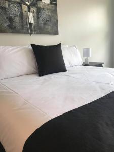 een groot wit bed met een zwart kussen erop bij Guiding Star Motel & Hotel in Brooklyn