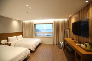 a hotel room with two beds and a flat screen tv at Am Ort Hotel in Yeosu