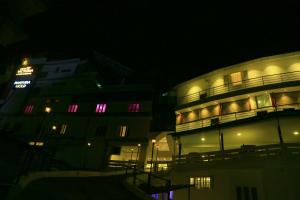 een nachtzicht op een gebouw met verlichting aan bij Hotel Victoria International in Kattappana