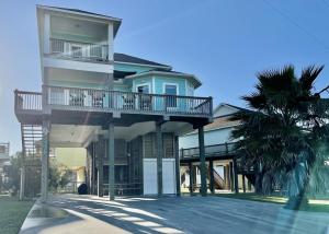 a house with a balcony and a palm tree at #Latitude Adjustment Home in Bolivar Peninsula