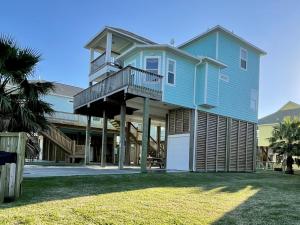 a blue house with a porch and a deck at #Latitude Adjustment Home in Bolivar Peninsula