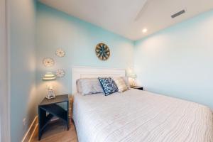 a bedroom with a white bed and a blue wall at West Side Cottage #OO in Gulf Shores