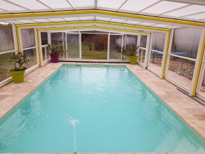 an indoor swimming pool with an open ceiling and windows at Gîte de la pouvellerie in Fossemagne
