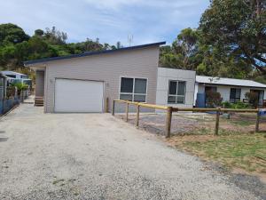 une maison avec un garage et une clôture dans l'établissement Pandora's Escape, à Venus Bay