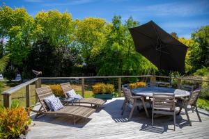 un patio con mesa, sillas y sombrilla en Swan House, en Martinborough