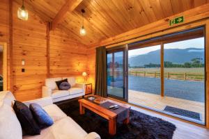 a living room with a couch and a large window at Deerbrooke Kaikōura Chalets - Chalet 1 in Kaikoura